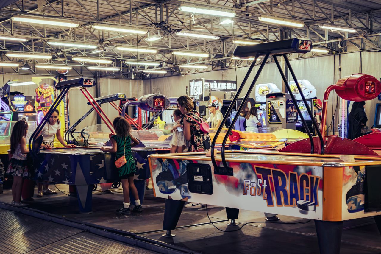 Children and adults enjoy air hockey games in a lively indoor arcade setting.