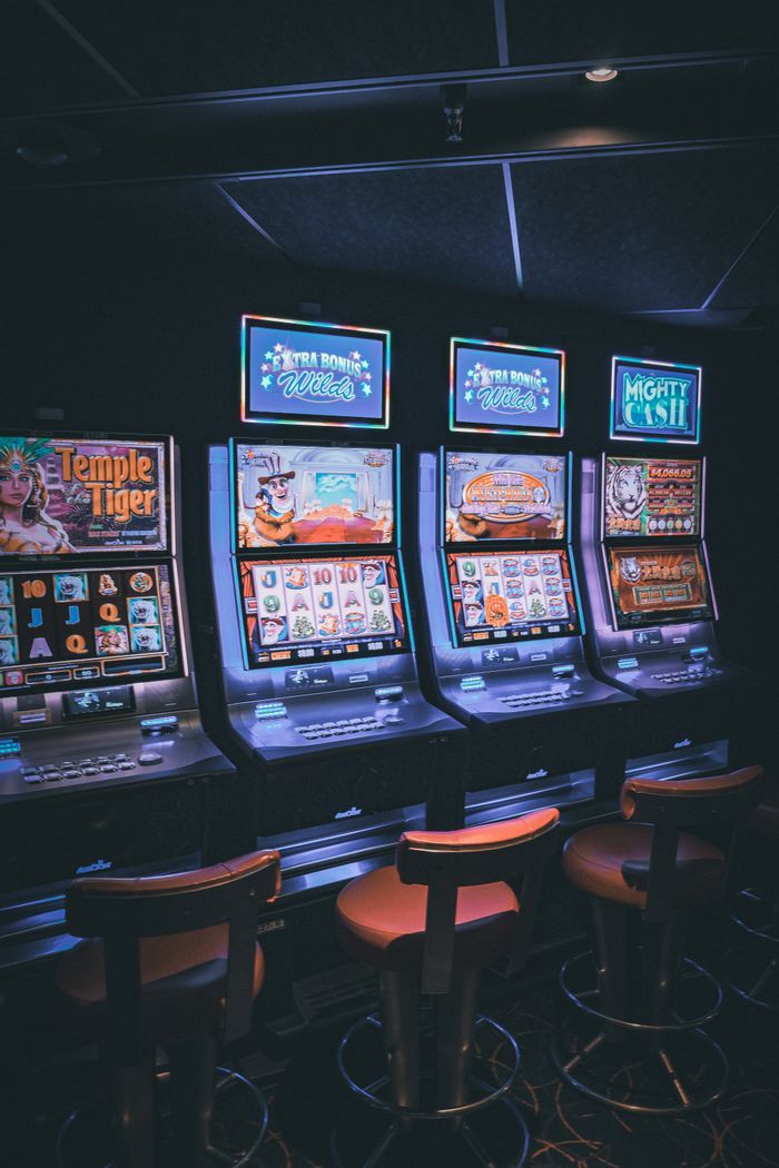 about-02 Row of illuminated slot machines in a dimly lit, empty casino area.
